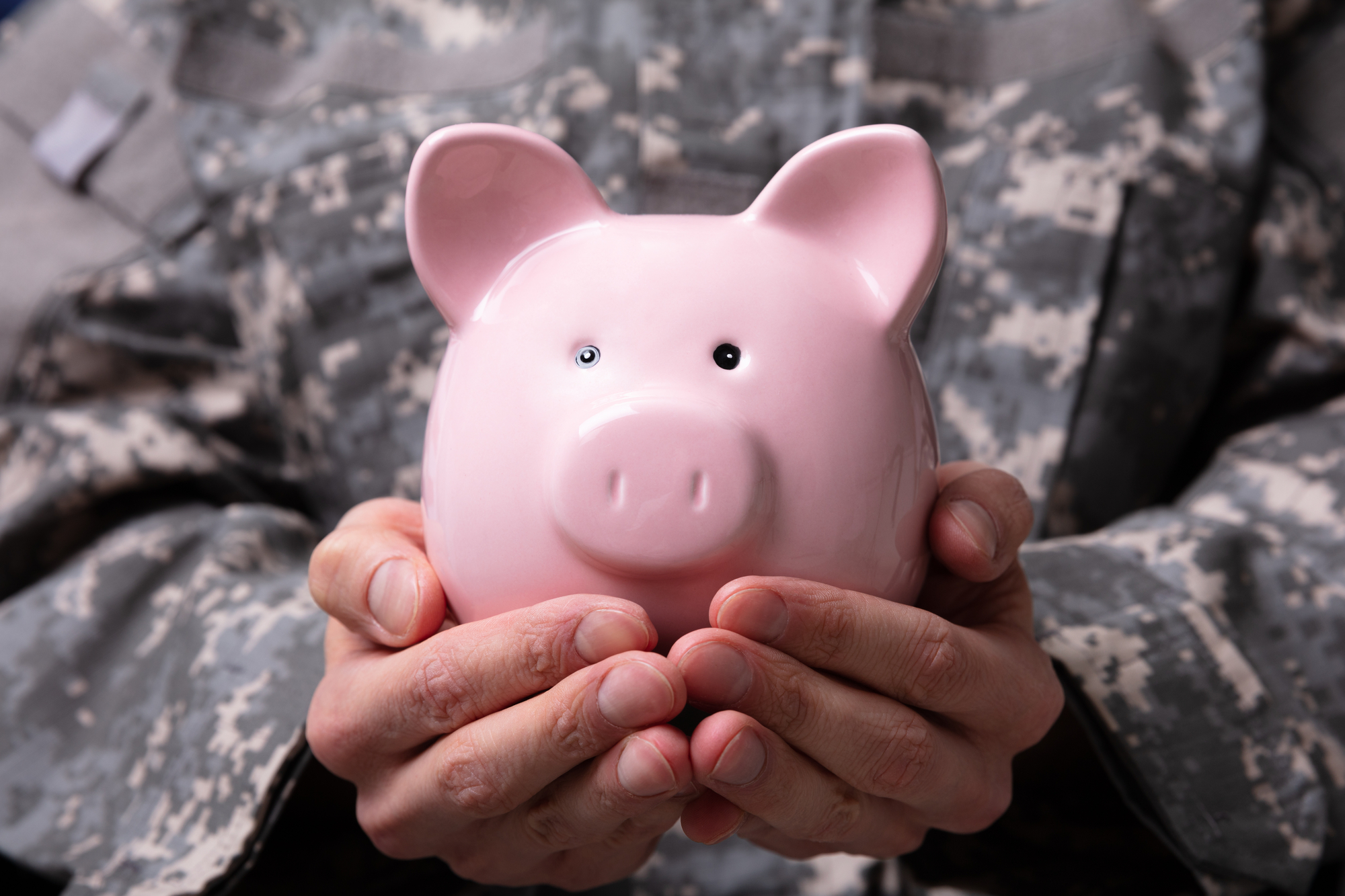 Close-up Of Soldiers Hand Holding Pink Piggy Bank