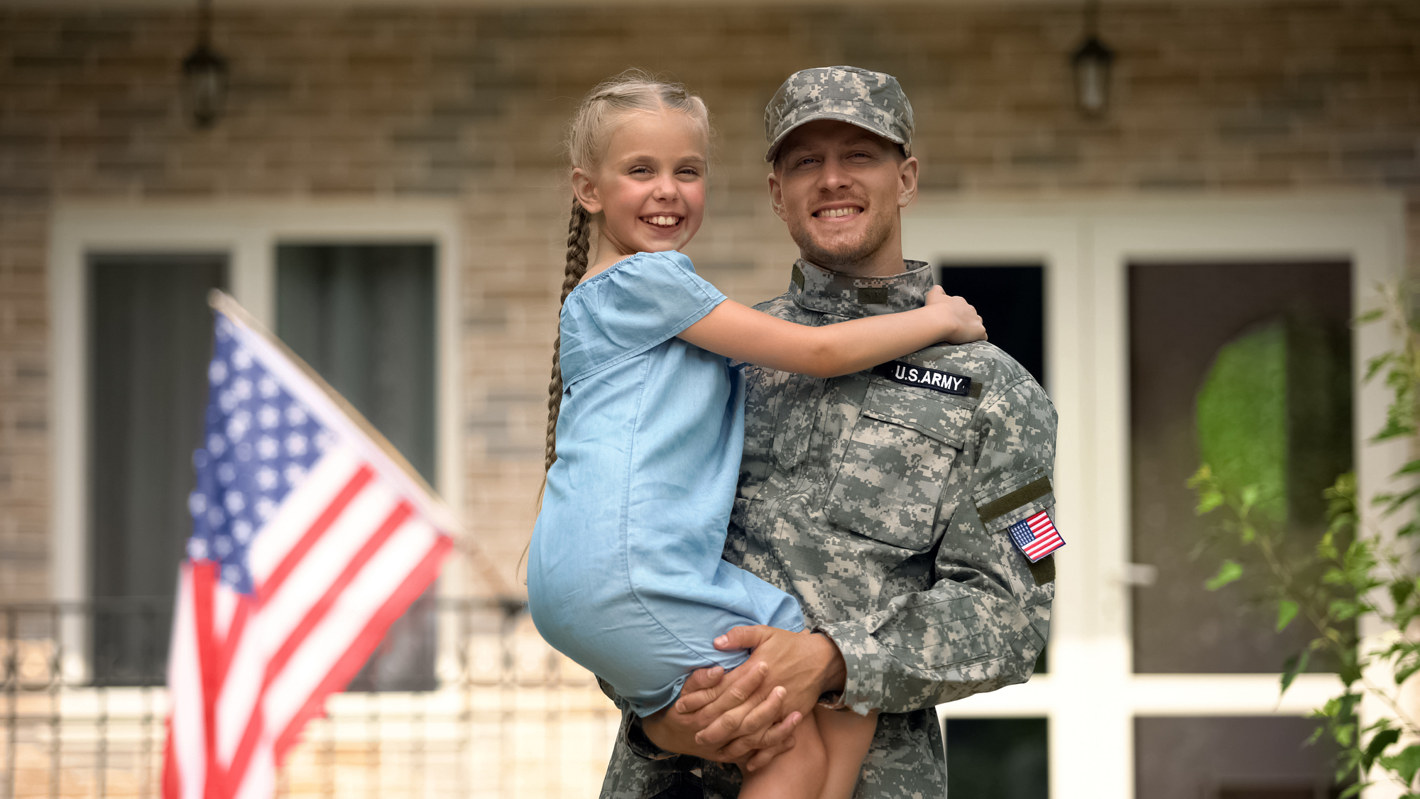Handsome USA soldier in military uniform holding happy daughter, homecoming