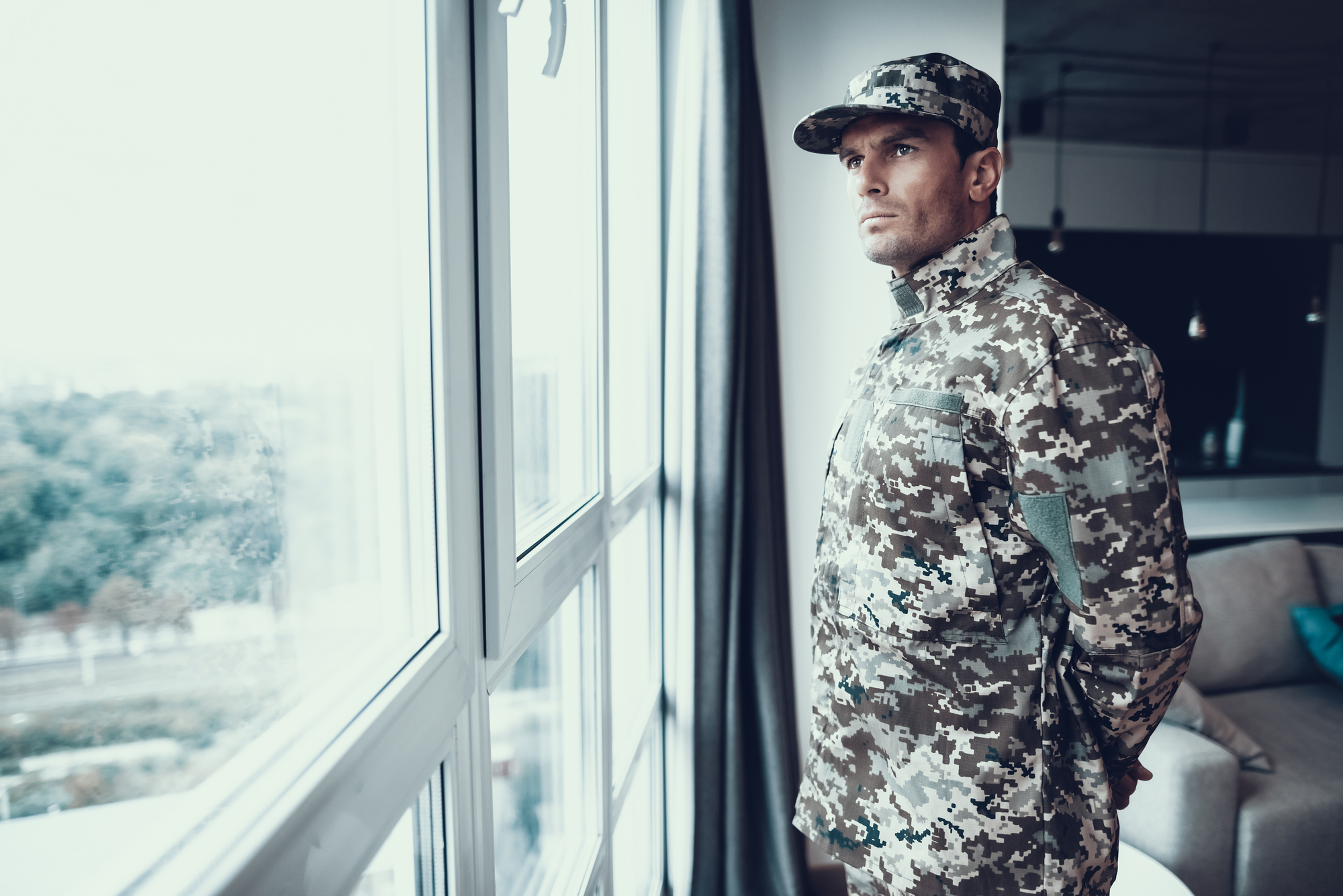Portrait of Man in Military Uniform Near Window. Serious Confident Thoughtful Person Standing in Modern Apartment Back and Looking at Large Panoramic Window.
