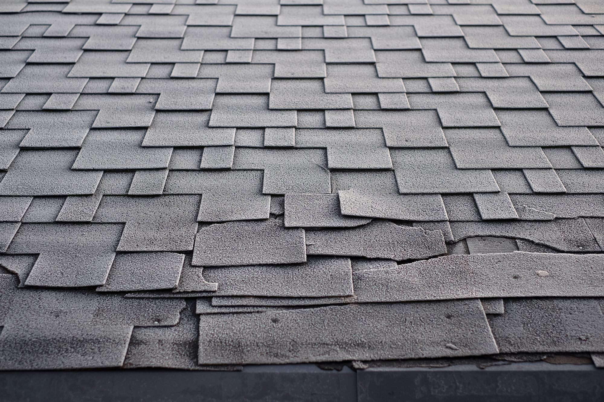 Shingles roof damage covered with frost. Close up view on Asphalt Roofing Shingles Background. Roof Shingles - Roofing